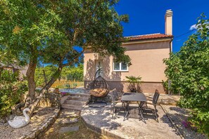 Una casa con patio, posti a sedere all'aperto, una scultura di cigno e una scala in pietra che conduce all'ingresso.