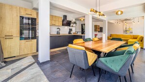 A modern kitchen with wooden cabinets, a built-in oven, and a dining area with a wooden table and chairs.