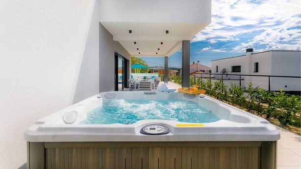 Un bain à remous dans un cadre extérieur moderne, offrant une vue dégagée sur le ciel et les bâtiments environnants.