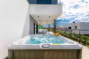 Un bain à remous dans un cadre extérieur moderne, offrant une vue dégagée sur le ciel et les bâtiments environnants.