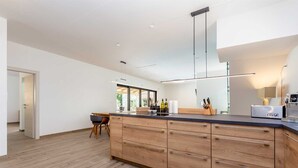 A modern kitchen with a wooden island, stainless steel appliances, and a large window providing natural light.