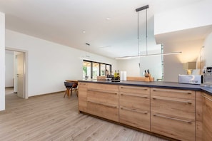 Una cocina moderna con una isla de madera, electrodomésticos de acero inoxidable y un amplio ventanal que proporciona luz natural.