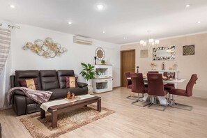 A living room with a sofa, coffee table, and dining area with chairs and a table.