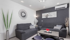 A modern living room with two grey sofas, a coffee table, and a decorative mirror.