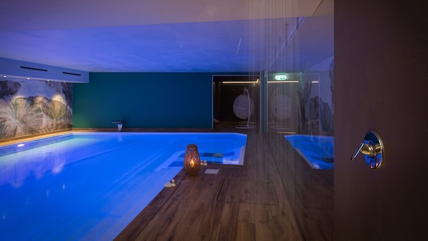 Ein modernes Hallenbad mit Holzboden, Steinwand und Glastür zu einem weiteren Raum.