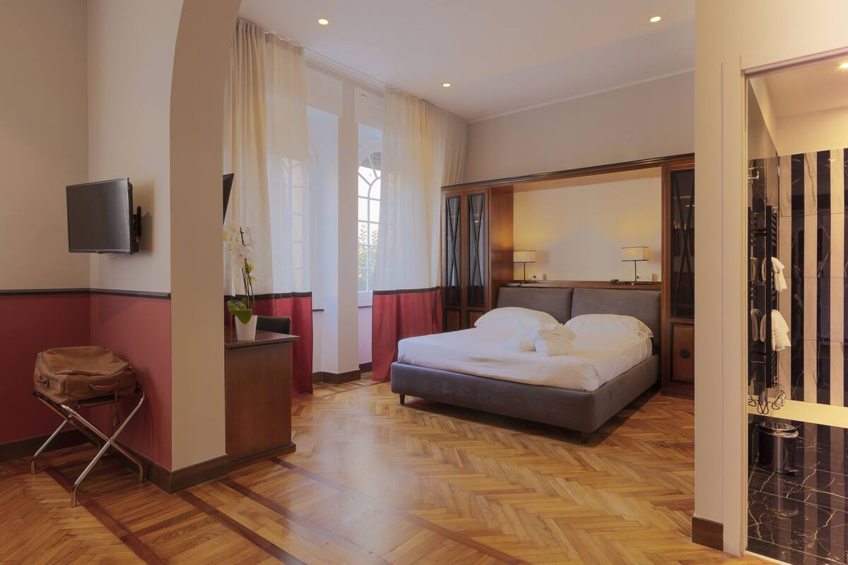 Hotelkamer met een bed, bureau, stoel, televisie en een badkamer met douche en toilet.