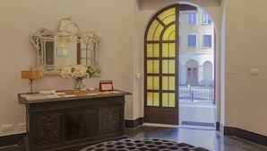 Eine Lobby mit dunklem Holzboden, einem dunklen Holztresen, einem Spiegel und einem Blumenstrauß.