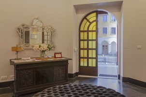 Eine Lobby mit dunklem Holzboden, einem dunklen Holztresen, einem Spiegel und einem Blumenstrauß.