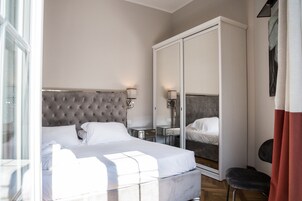 Ein modernes Hotelzimmer mit einem großen Bett, einem Kleiderschrank, einem Schminktisch mit Spiegel und einem kleinen Tisch.