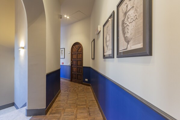 Un pasillo con puerta de madera, obras de arte enmarcadas en las paredes y una decoración azul y blanca.