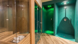 Ein modernes Badezimmer mit Holzboden, einer Duschkabine aus Glas und einer Wand in Grüntönen.