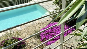 En pool med utsikt över bergen och en trädgård med lila blommor.