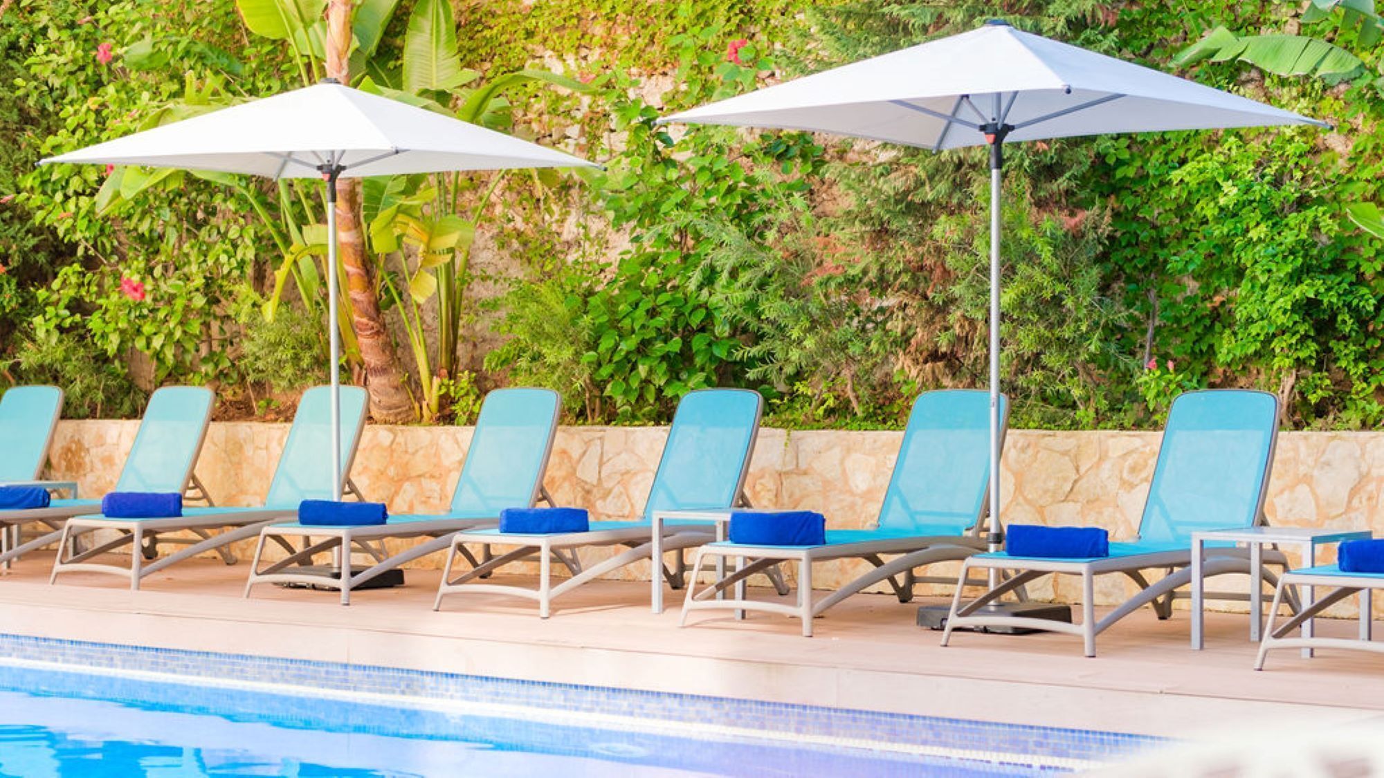 A poolside area with lounge chairs and umbrellas.
