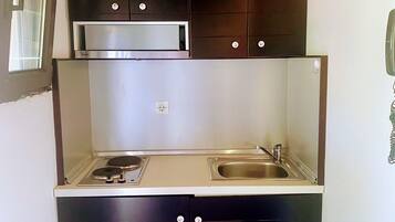 Una cocina compacta con armarios oscuros, estufa de acero inoxidable y horno empotrado.