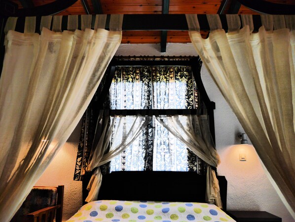 Un dormitorio con cama, cortinas y una ventana con cortinas estampadas.
