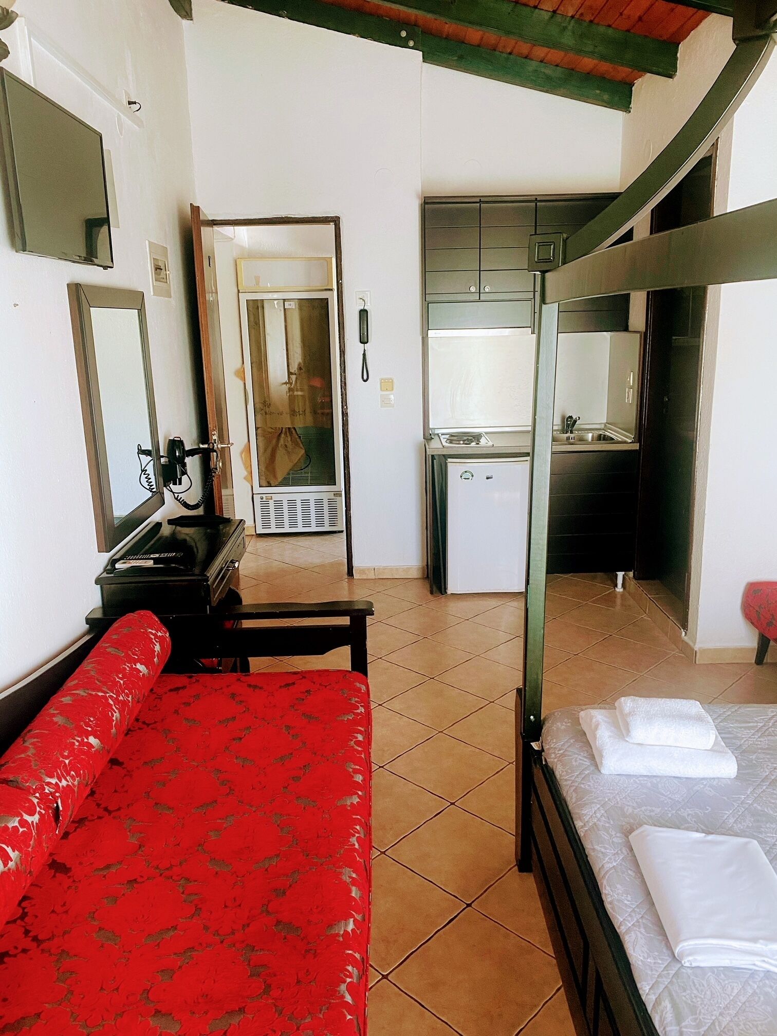 A room with a bunk bed, a desk with a chair, a small kitchenette, and a bathroom.