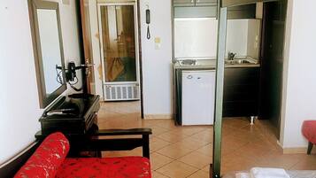 A room with a bunk bed, a desk with a chair, a small kitchenette, and a bathroom.
