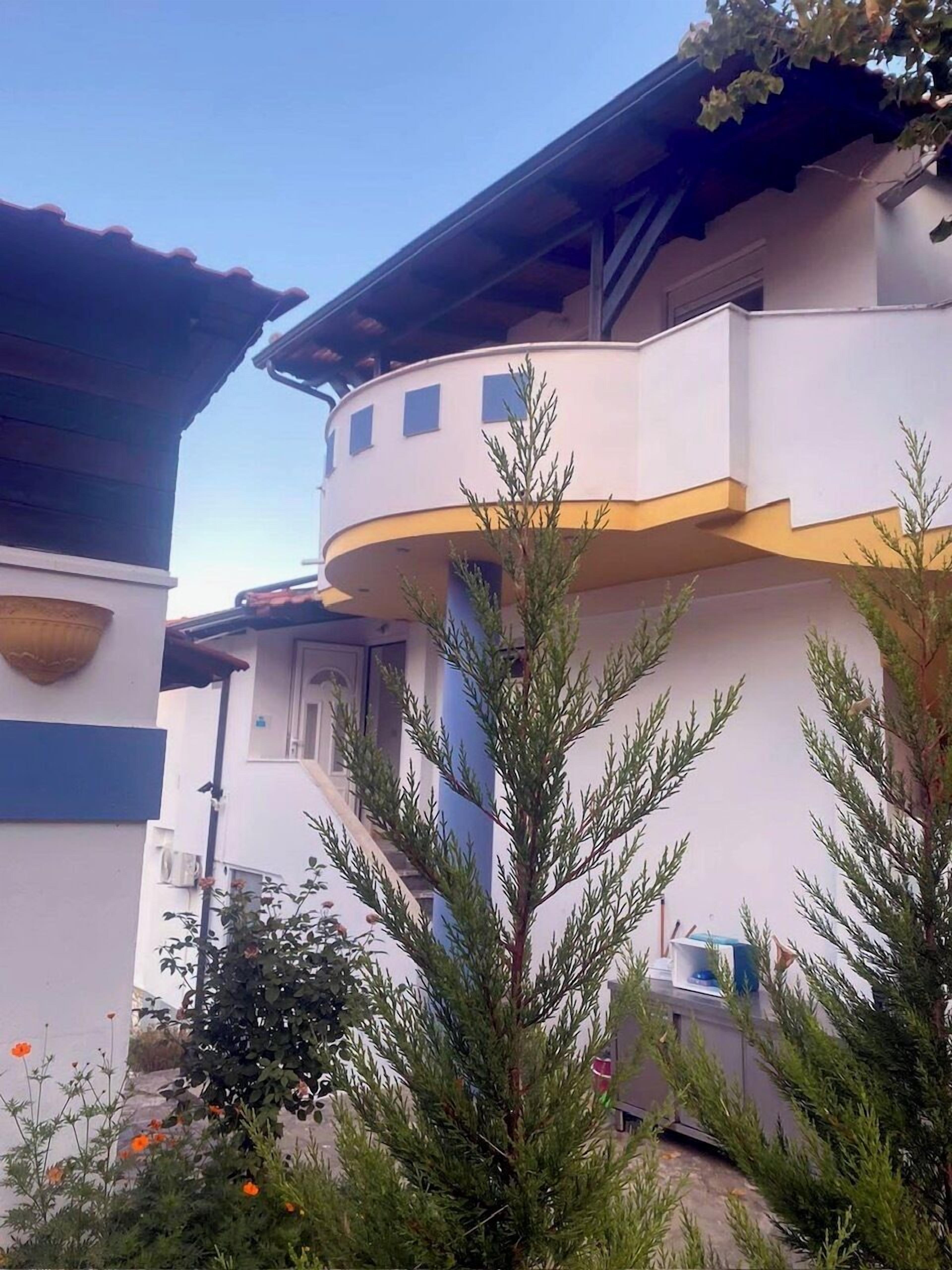 A multi-story building with a curved balcony, a small window, and a door.