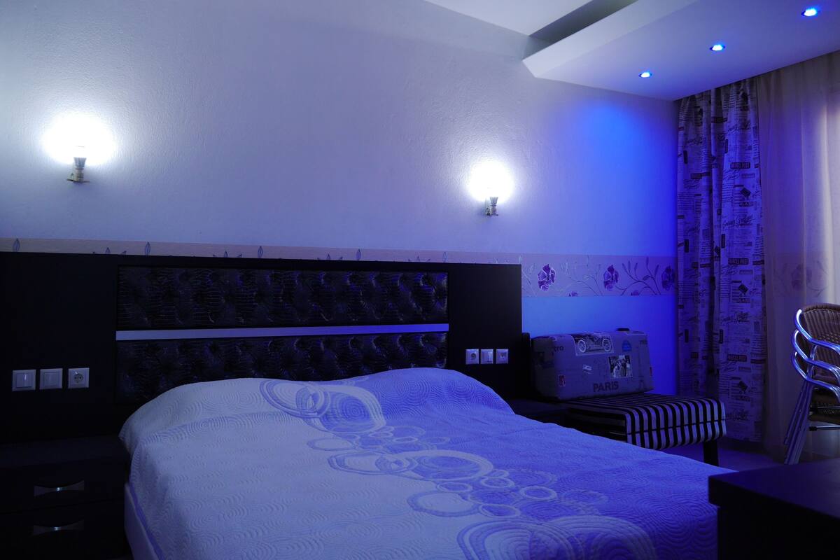 A hotel room with a bed, bedside tables, a chair, and a suitcase.