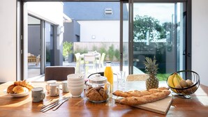 A breakfast table with croissants, muffins, a pineapple, bananas, and a glass of orange juice. - Villa Odet O Bord de l'O Piscina coberta 29°C em Sainte Marine, praia 100m (Combrit)