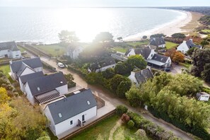 Ett bostadsområde vid kusten med hus, en strand och fri utsikt över havet.