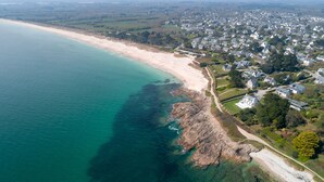 An aerial view of a coastal town with a beach, residential areas, and a mix of houses and larger buildings. - Villa Odet O Bord de l'O Piscina coberta 29°C em Sainte Marine, praia 100m (Combrit)