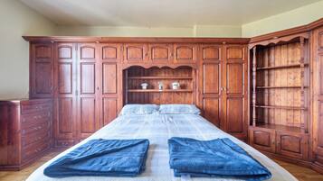 A bedroom with a large bed, wooden wardrobe, and a dresser.