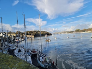 Un port de plaisance où sont amarrés de nombreux bateaux, avec une eau calme et un paysage vallonné en arrière-plan.