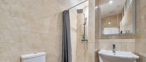 A bathroom with a toilet, shower, bathtub, and sink.