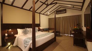 A spacious hotel room with a large bed, a desk, a chair, and a ceiling fan.