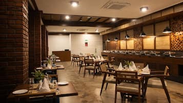 A restaurant with brick walls, wooden tables, and a buffet area.