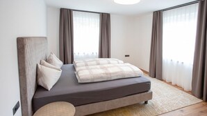 A modern bedroom with a bed, curtains, and a round table. - Vacation apartment for up to 8 people (Latsch/Morter)