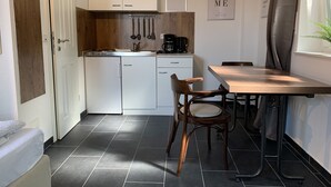 A compact kitchen with white cabinets, a wooden countertop, and a dining area with a table and chairs. - Bernsteinsucher (Norden)