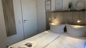 A bedroom with a wooden headboard, a bed with patterned bedding, a white door, and wall-mounted light fixtures.