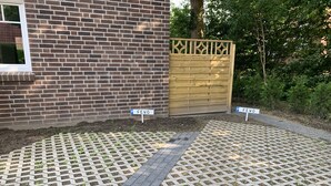 A paved driveway with a brick wall and a wooden gate. - Bernsteinsucher (Norden)