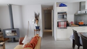 A living room with a sofa, a fireplace, a dining area with a table and chairs, and a kitchen with appliances. - Villa near village center (Pradelles)