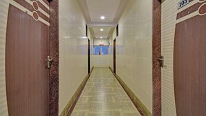 A hallway with tiled walls, a patterned floor, and doors marked with numbers. - Treebo Paradise Inn, Panchgani (Mahabaleshwar)
