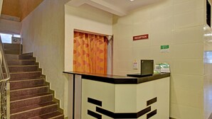 A reception desk with a patterned curtain, a reception sign, and a laptop on the counter. - Treebo Paradise Inn, Panchgani (Mahabaleshwar)