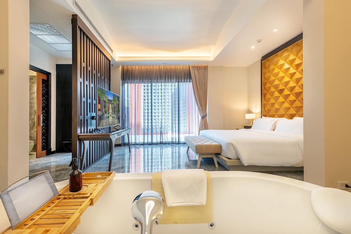 Een hotelkamer met een groot bed, een zithoek, een ligbad en een televisie.