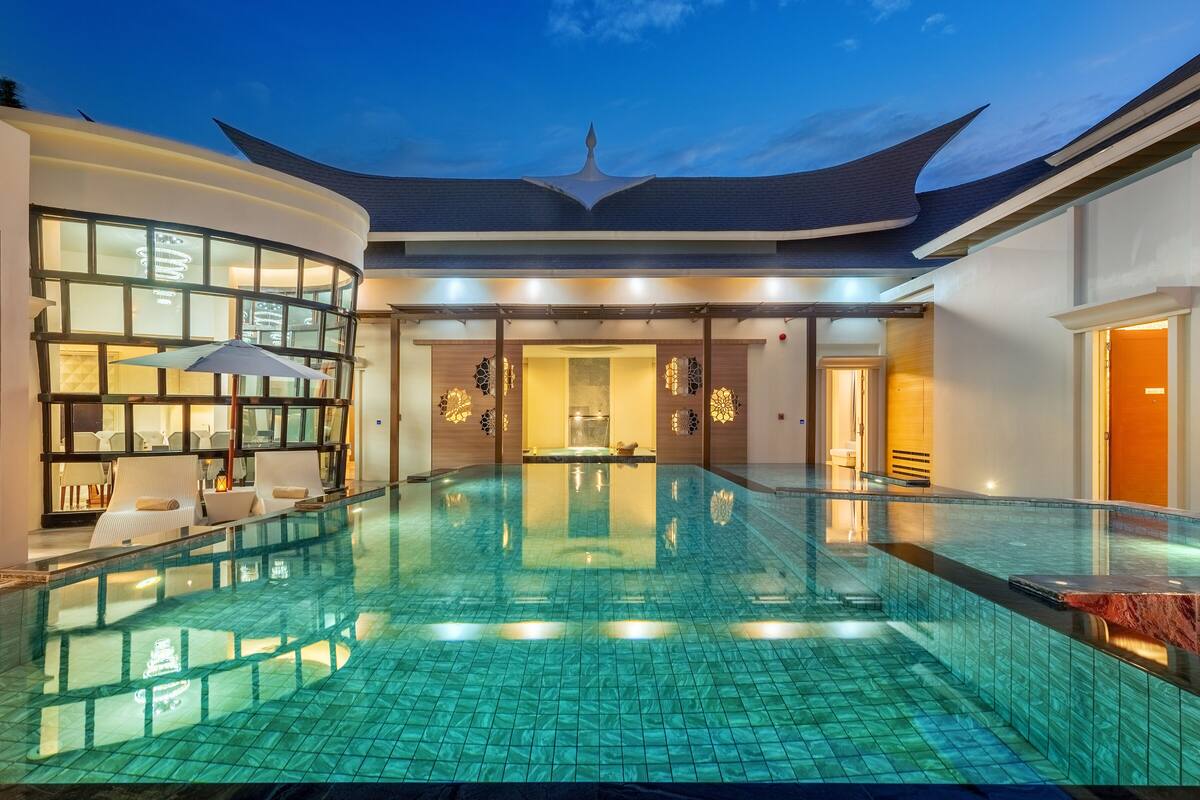 Een modern hotel met een groot binnenzwembad, een lounge met zitplaatsen en een opvallend dakontwerp.