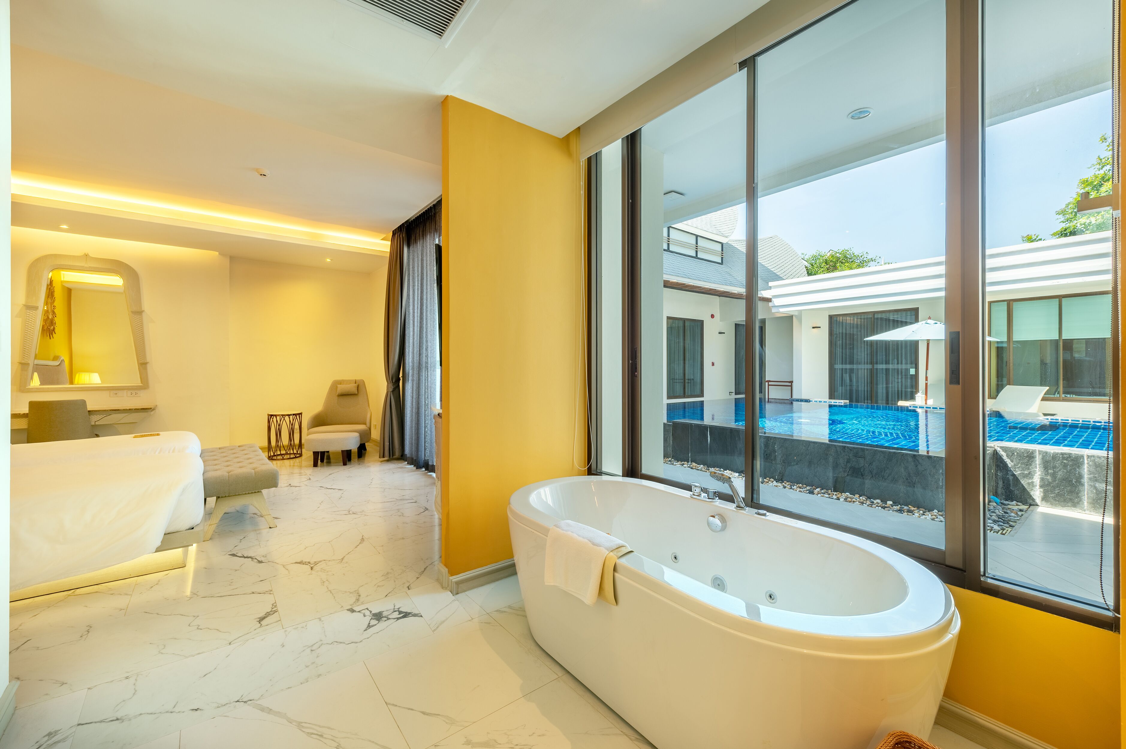 Un baño moderno con una bañera grande, una cama doble y vistas a una piscina exterior.