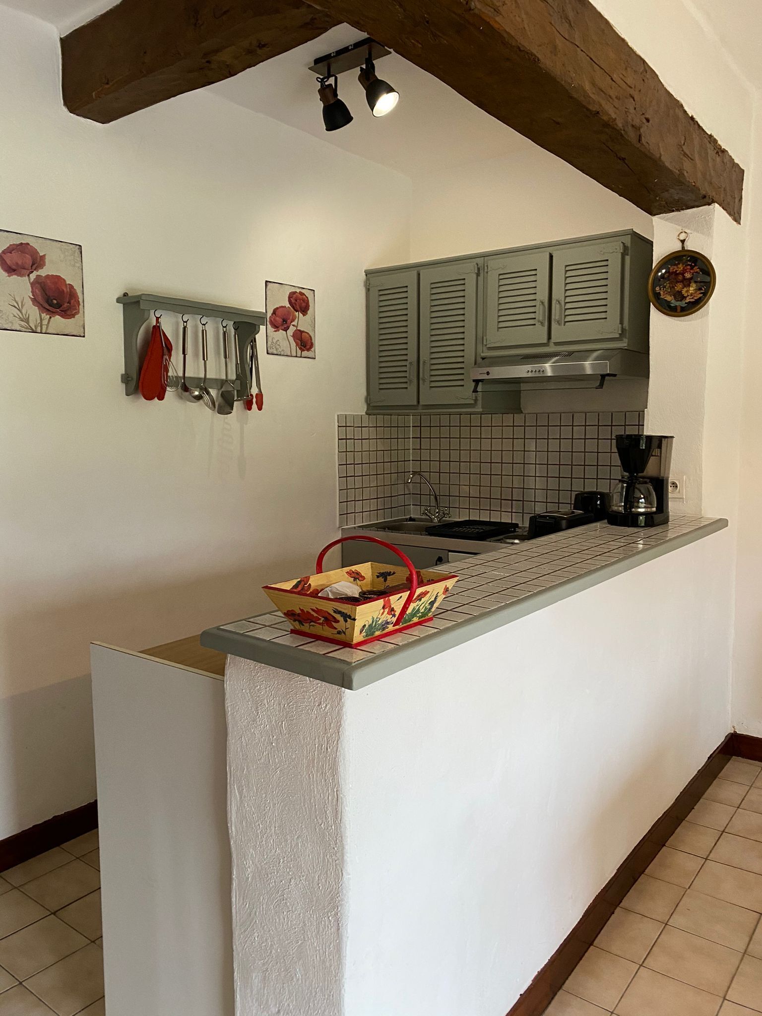 A kitchen with a central island, a hanging pot rack, and a coffee maker on the counter.