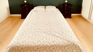 Ein Schlafzimmer mit einem Einzelbett, dunkelgrünen Wänden, Holzboden und zwei Nachttischen mit Lampen.