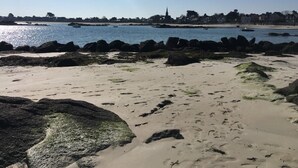 Ein Strand mit Felsformationen und einer entfernten Ansicht einer Stadt.