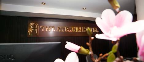 A reception desk with a sign reading "THE ATRIUM HOTEL" and a modern interior design.