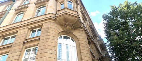 A corner of a building with classical architecture, featuring a prominent arched window and decorative stonework.