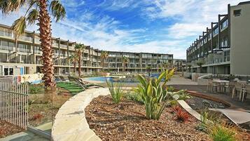 A resort with a pool, palm trees, and a landscaped garden.