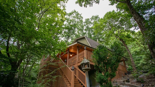 Una cabaña de madera con balcón, rodeada de un bosque frondoso.