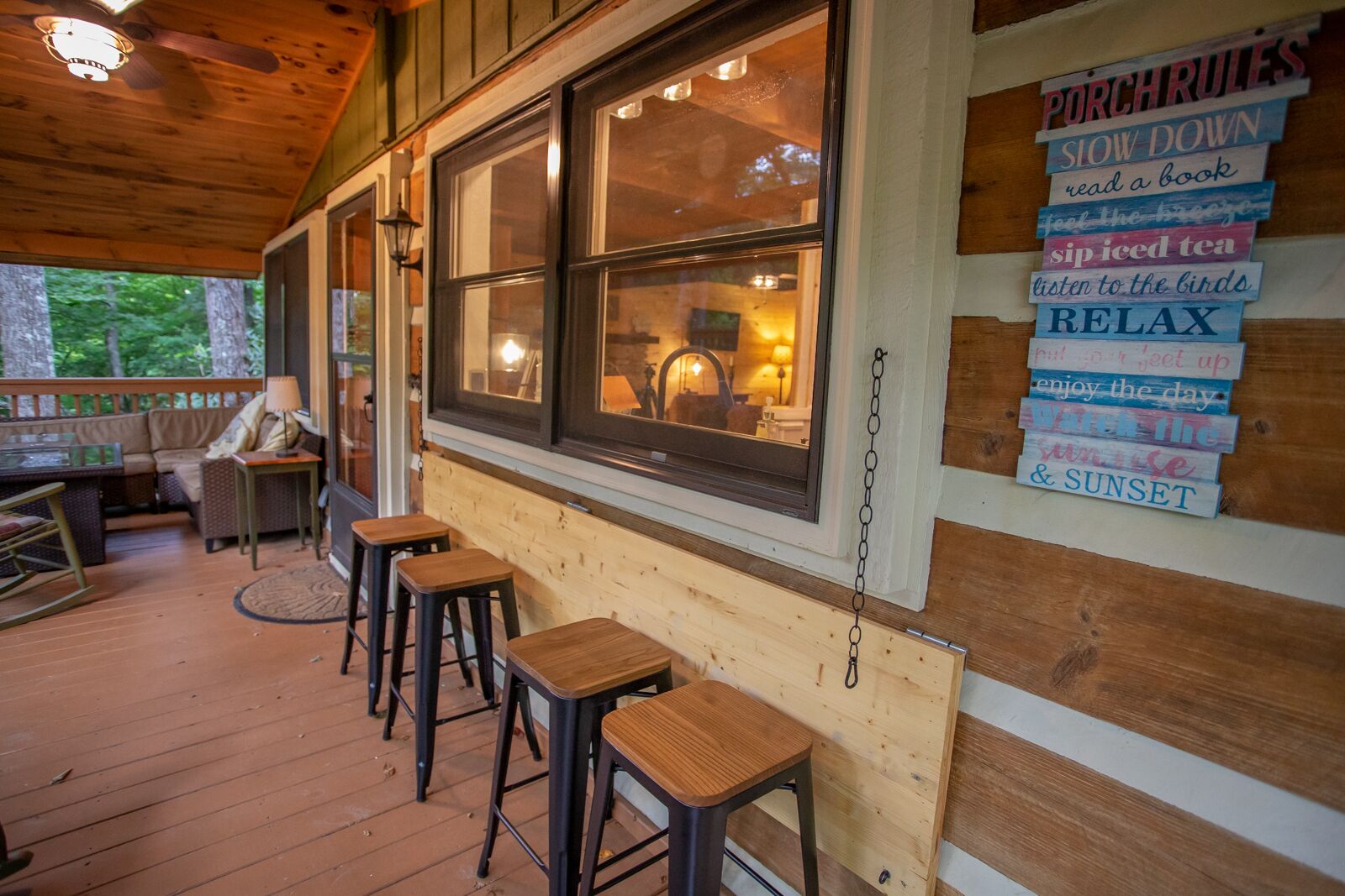 Une terrasse en bois accueillante, avec un coin bar, des tabourets en bois et une vue sur l’intérieur grâce à de grandes fenêtres.