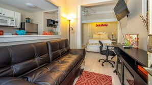 A compact living space with a kitchenette, a sofa, a desk, and a bed.